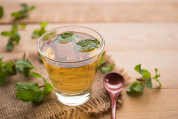 Tea peppermint in glass with leave mint on wood background. herb drink concept.