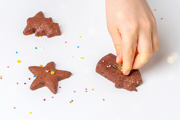 Cooking Christmas and  New Year chocolate cookies or gingerbread. Traditional festive baking, bake with kids. Child hands Decorate baked gingerbread with multi-colored sweet sprinkles;;