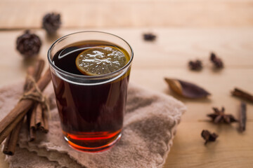 Autumn hot tea concept. hot tea in glass with spices and falling leaves around on wood. drink of winter and drink for health.