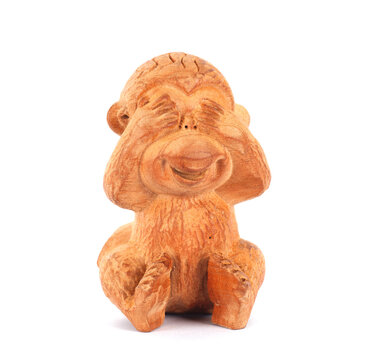 Wood carving of little monkey covering eyes on white background