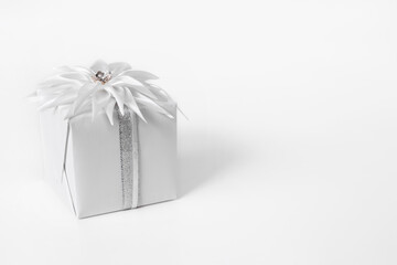 Giftbox with ribbon flower on white background. Monochrom. Copy space
