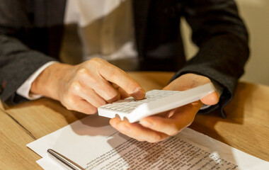 Calculating budget at office desk, close up of male hands