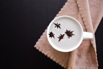 Fototapeta na wymiar Hot drink for autumn winter concept. Hot milk with star anise spice fruits in white cup on wood background. flat lay view with copy space. drink for health in holidays.