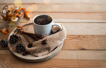 Fototapeta na wymiar Hot drink for autumn winter concept. black tea in white cup with star anise spice fruits, cinnamon, dry orange peel on wooden with yellow bokeh background.