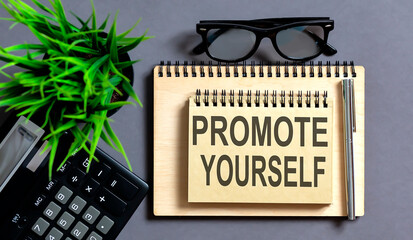 Text PROMOTE YOURSELF on the notepad with office tools, pen