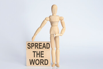 Wooden man shows with a hand text SPREAD THE WORD concept on wooden block