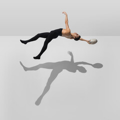 Fototapeta premium Inspiration. Stylish young male athlete on white studio background with shadows in jump, air flying. Sportive fit model in motion and action. Body building, healthy lifestyle, style concept.