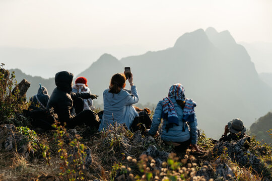 Chiang Mai, Thailand. Feb 18, 2019: Adventurer and tourists wearing an Insulated coat, jacket and scarf, taking photos of mountains and dusk near the sunset in the background of Doi Luang, Chiang Dao.