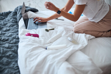 Fototapeta premium Modern roller massager lying on white bed near pretty lady in home apartments