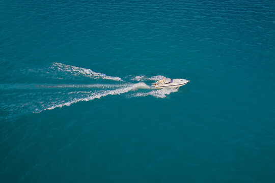 Large speed boat moving at high speed side view. Travel - image. Drone view of a boat  the blue clear waters. Modern boat with the flag of Germany on turquoise water.