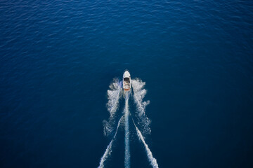 Drone view of a boat sailing across the blue clear waters. Aerial view of luxury floating ship at...