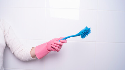 a female hand in a glove holds a washing brush