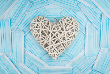 White heart on a background of a blue faces masks. Concept of a Valentines day during Coronavirus or Covid pandemic.