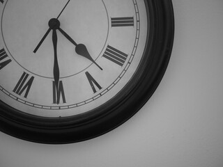 Close up of wall clock with roman numeral numbers in black and white