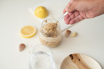 Tahini, lemon and garlic on the white table. How to cook tahini. First step for cooking. Glass of water and tahini. Tahini different from hummus. Traditional food. step 3
