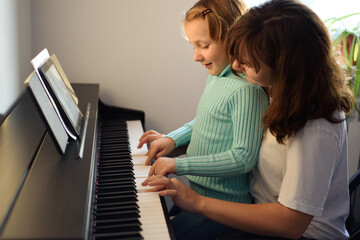 Fototapeta na wymiar Mom and daughter play the piano together
