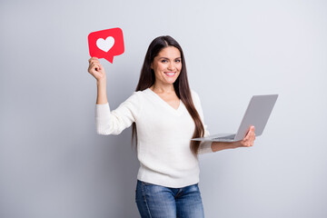 Portrait of attractive cheerful girl holding in hands using laptop paper like card isolated over...