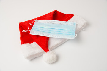 Santa hat and medical mask on white background close up with copy space