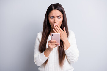 Fototapeta premium Portrait of lovely focused worried brown-haired girl using device reading bad news comment isolated over grey pastel color background