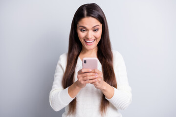 Fototapeta premium Portrait of attractive focused cheerful brown-haired girl using device reading news having fun isolated over grey pastel color background