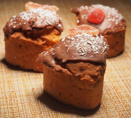 Three handmade cupcakes. Homemade cupcakes are decorated with chocolate icing, coconut chips, and marmalade.