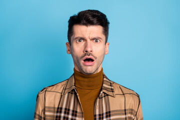 Portrait of young shocked amazed scared afraid speechless man with open mouth isolated on blue color background