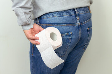 Man feeling pain and holding toilet paper roll, diarrhea, hemorrhoids or constipation