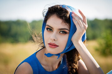 Portrait of a beautiful sexy girl in a blue headscarf and dress on a sunny day