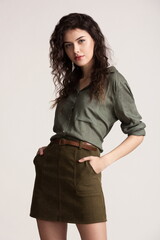 Beautiful sexy girl in a short green skirt and shirt posing in the studio on a white background