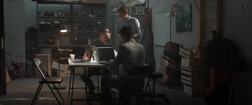 Friends having a pizza break from working. Launching their small IT business startup company from garage. Shot with 2x anamorphic lens
