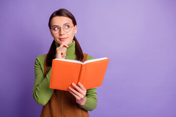 Portrait of lovely brainy cheery minded girl reading book creating decision copy space isolated over pastel violet color background