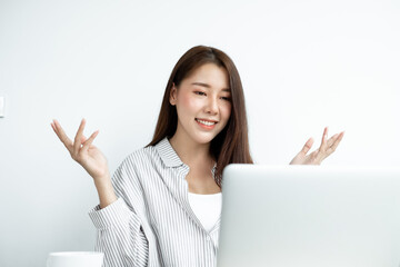 Video call, a young Asian woman communicates via online video long distance, looking at the digital laptop screen, happily greeted with a friend