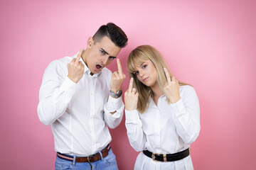 Young couple of girlfriend and boyfriend over isolated pink background showing middle finger doing...