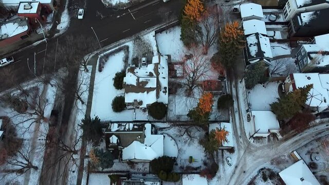 1-2 aerial pan out birds eye view over winter urban luxury home during a sunset tree tip lit branches with wet snowy slushed roads light traffic in a rich residential community with curvy sideroads