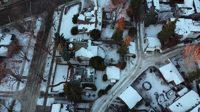 2-2 aerial forward birds eye view over winter urban luxury home during a sunset tree tip lit branches with wet snowy slushed roads light traffic in a rich residential community with curvy sideroads