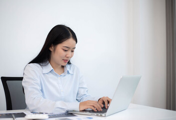 An Asian woman looks good and is pretty working on a laptop Business women are busy working with laptop computers in the office