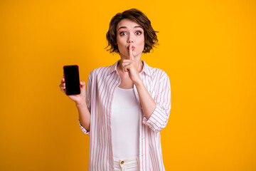 Photo astonished girl hold smartphone put finger lips ask dont share hush speechless voiceless...