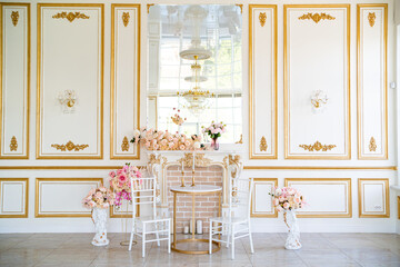 interior with gold stucco, mirror, flowers in vases and decorative fireplace.