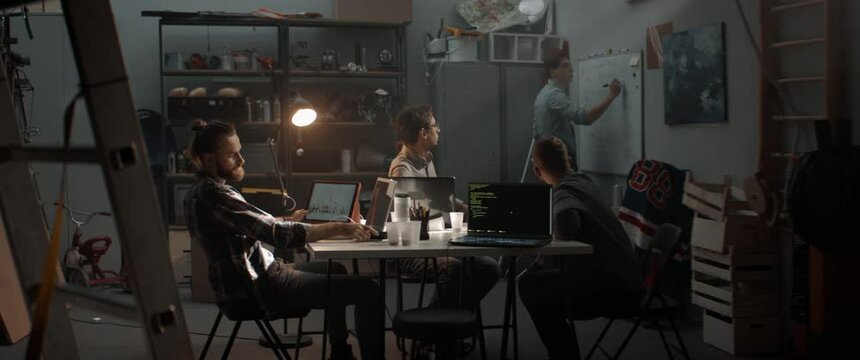 Young people celebrate after receiving good news call from client or investor, small business concept. Launching their small IT startup company from garage