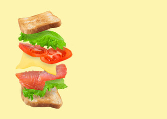 Flying sandwich with salmon, cheese and tomatoes isolated on a yellow background. Fast food concept. Copy space