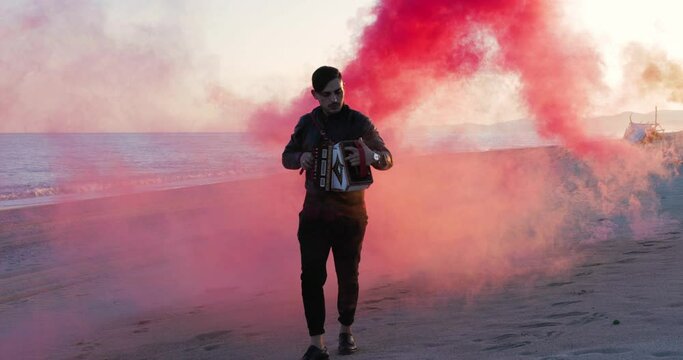 Ragazzo suona la tarantella calabrese con l'organetto in spiaggia vicino al mare