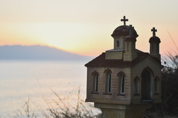 Fototapeta na wymiar A Greek orthodox miniature church in the sunset at the sea