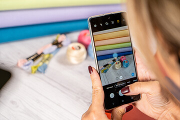 A woman takes a photo on a smartphone. Accessories for hobby embroidery knitting