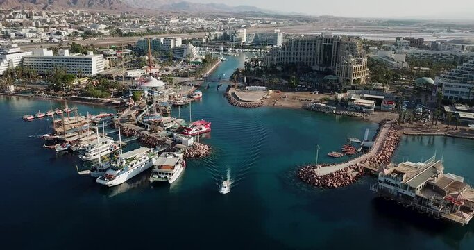 Aerial birds eye view video taken of Eilat, Israel. A Drone shot city landscape view of tourist city in the desert with crowded port with boats docked at marine. luxury vacation concept shot 