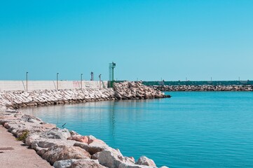 A green lighthouse on the pier of Pesaro harbor with tetrapod breakwaters (Marche, Italy, Europe)