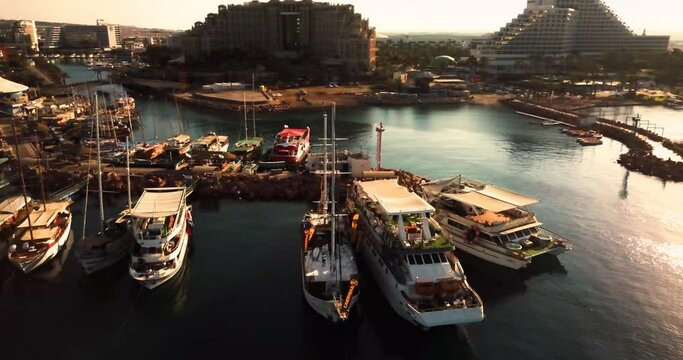 Aerial shot above Eilat, Israel. Drone above marina port boats at the sea water or ocean at a desert tropical landscape with hotels and tourist attractions. 