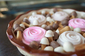 Simple Christmas sweets platter from pink and white marshmallow roses and brown and white cookies in form of mushrooms with chocolate caps