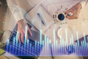 Multi exposure of man's hands typing over computer keyboard and forex graph hologram drawing. Top view. Financial markets concept.