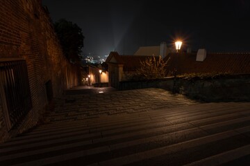 .street lights and pedestrian sidewalk with cobblestones in the center of Prague at night and in the background city view at night