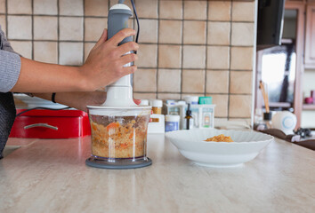 Young grinds and mixes the vegetables ingredients in a blender. Healthy eating concept. 